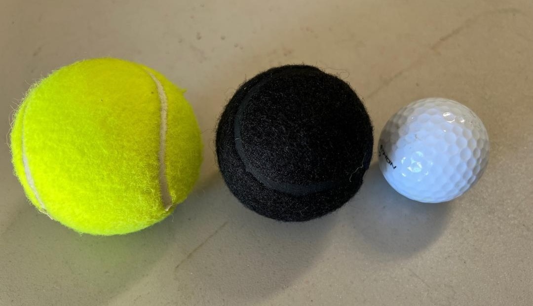 Tennis ball size comparison: yellow, black, golf ball